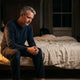 Man winding down on the edge of his bed by lamplight — natural sleep aids without melatonin
